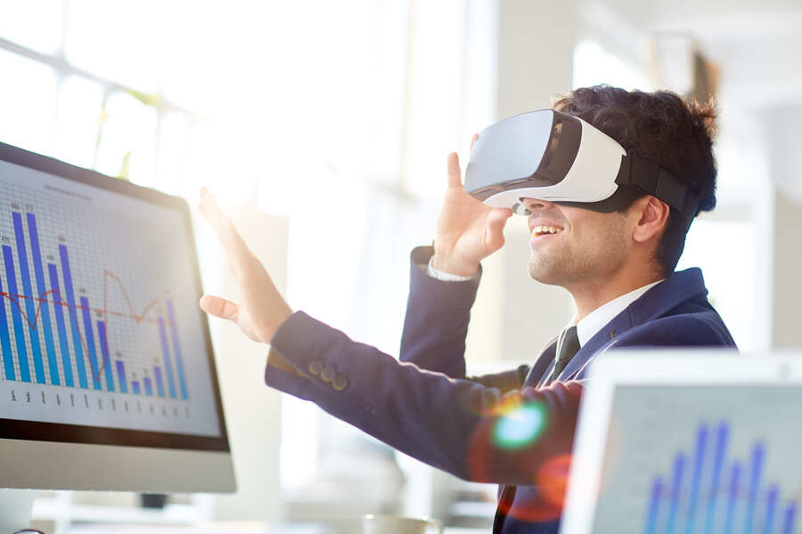 Happy manager with virtual reality goggles touching imaginary world